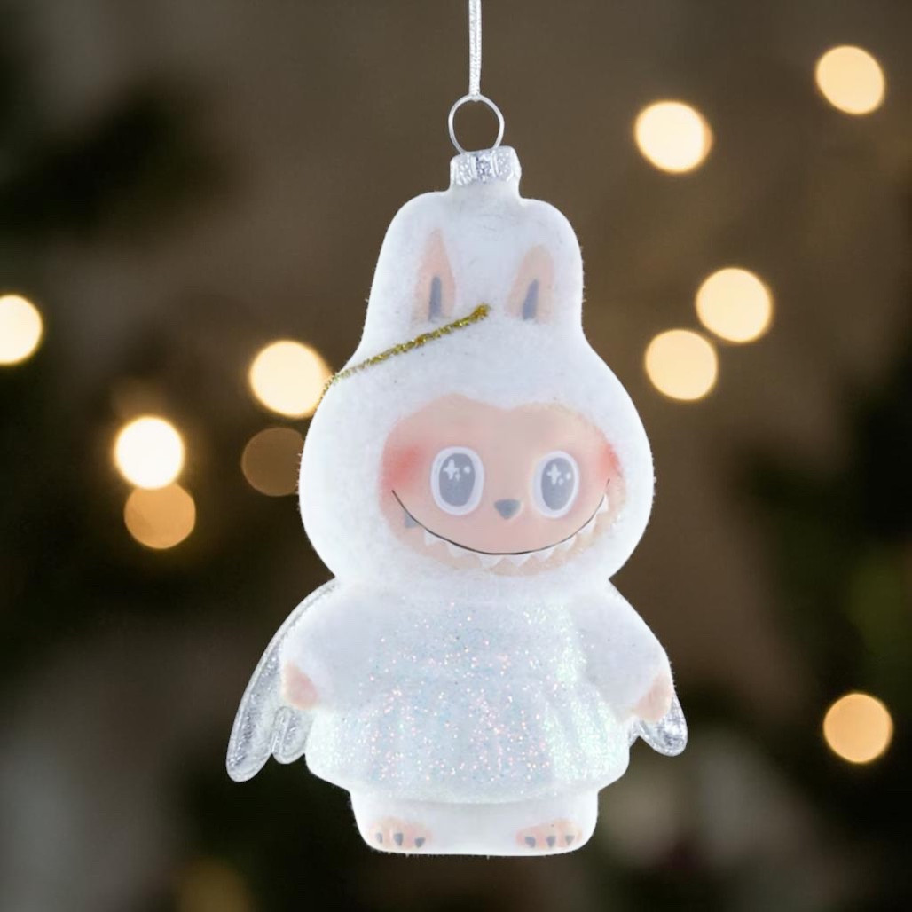 Fuzzy white monster angel glass ornament with silver wings and hanging loop.
Whimsical smiling character ornament with glittery body and soft pastel details.
4.75 inch glass monster angel Christmas ornament on a white background.