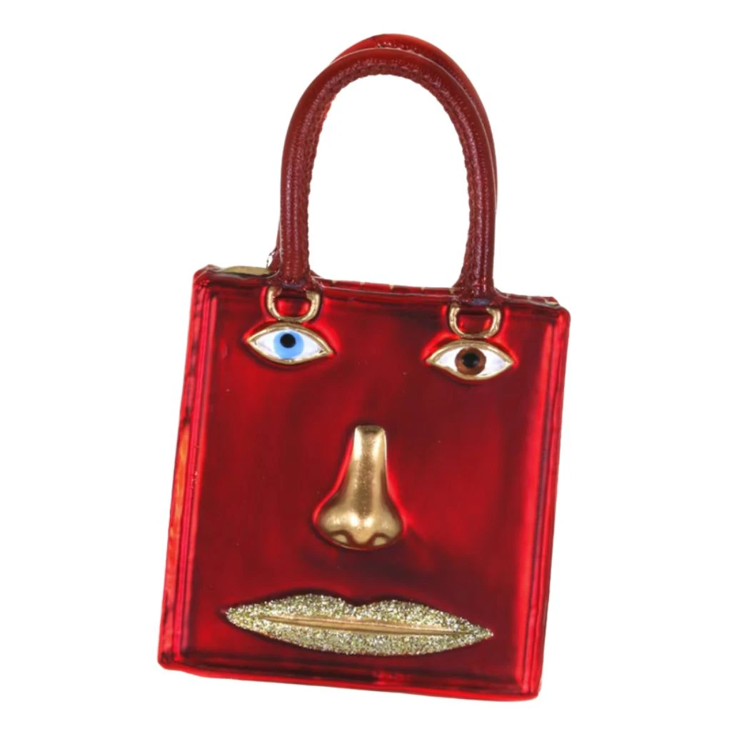 Red glass handbag ornament with face design, gold nose, and glitter lips.
Fashion-themed purse ornament with two handles and mismatched eye details.
4.25 inch Le Visage Bag glass ornament