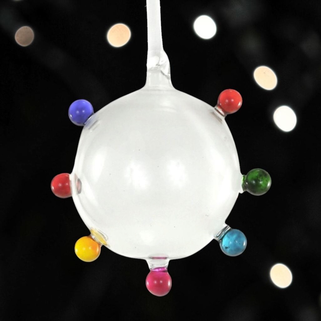 Clear glass bauble ornament with multicolor raised dot accents.
Round dotty Christmas ornament with red, blue, green, yellow, and pink details.
Glass Dotty Bauble Multi ornament hanging from a white ribbon.