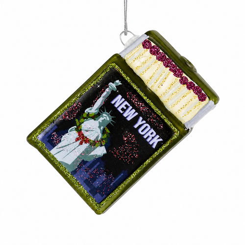 Glass New York souvenir matchbox ornament with green frame and Statue of Liberty artwork.
NYC travel Christmas ornament with New York text and glittered match details.
3 inch glass matchbox ornament with decorative matches and silver hanging cord.