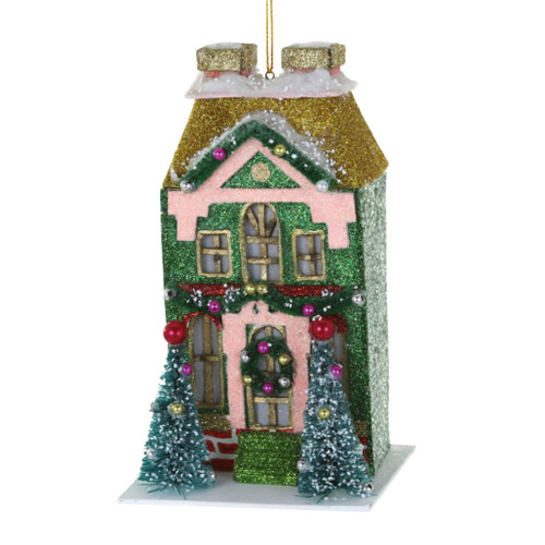 Green vintage house Christmas ornament with pink trim and gold roof.
Paper mache house ornament with snowy details, wreath, and front trees.
Hanging vintage-style house ornament measuring 3.25 x 2.75 x 5.5 inches.