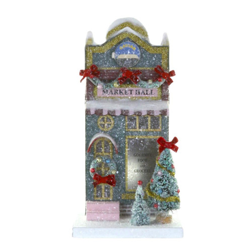 Glittered cardboard Market Hall with snowy roofline, garland, red bows, and gold trim.
Christmas village market building with front wreath, decorated trees, and storefront signs.
Holiday market hall decoration measuring 6.75 x 7.5 x 12.5 inches.