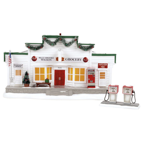 Department 56 Snow Village Billy Brooks Grocer building with white storefront, red doors, garland, and warm windows.
Rear view of Billy Brooks Grocer showing USB light cord, adapter, snowy roof, chimney, and white clapboard siding.
Snow Village grocery building with vintage gas pumps, vending machine, American flag, post office sign, and snowy base.