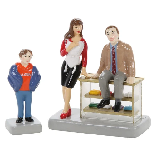 Department 56 Snow Village Christmas Vacation accessory with Russ figure beside Mary and a seated shopper at a counter.
Can't See Line Can You Russ? figurine set showing store counter, folded items, Mary, seated man, and Russ figure.
Side view of Russ figure in blue jacket and orange Illinois hoodie on a gray base.