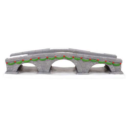 Department 56 Walking Bridge porcelain accessory with gray stone arches and snowy details.
Cross Village walking bridge with green garland, red ornaments, and snow-covered base.
Porcelain village bridge accessory measuring 9.5 inches long for holiday display pathways.