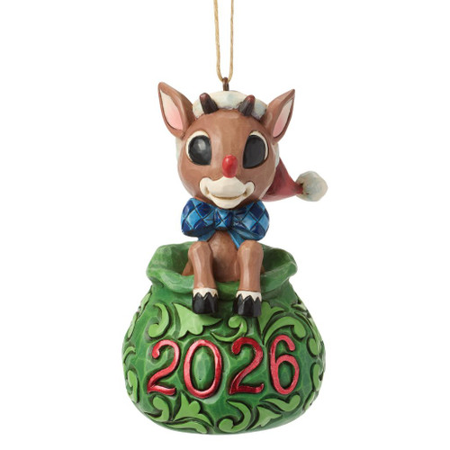 Jim Shore Dated 2026 Rudolph in Bag ornament featuring Rudolph peeking from Santa's green toy bag.
Hand-painted stone resin Rudolph Traditions ornament with 2026 date and folk-art rosemaling details.
Christmas tree ornament of Rudolph wearing a Santa hat inside a decorative holiday gift bag.