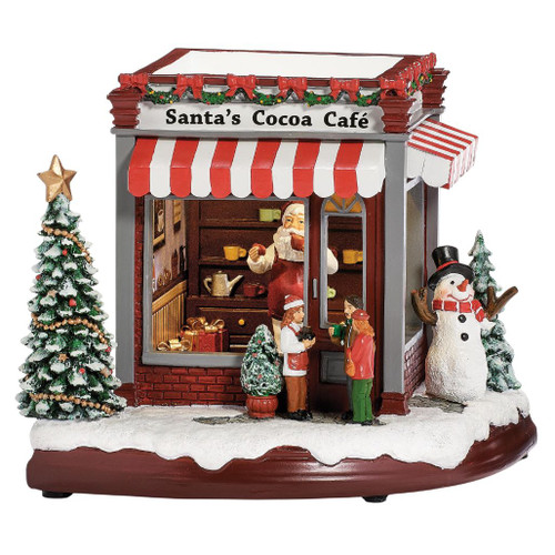 Santa’s Cocoa Cafe resin Christmas figurine with striped awning, Santa, customers, snowman, and snow-covered trees.

LED rotating musical Santa Cocoa Cafe scene measuring 7.5 inches high by 8.25 inches wide and long.

Snowy Santa Cocoa Cafe Christmas village scene with decorated tree, café storefront, Santa, gifts, visitors, and snowman.