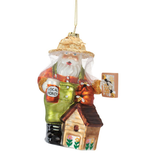 5.5-inch glass Santa beekeeper ornament with protective veil, straw-style hat, and beehive.

Santa beekeeper Christmas ornament holding a Local Honey jar with bees and honeycomb details.

Glass Santa ornament with green overalls, beekeeping veil, honey jar, bees, beehive, and floral accents.