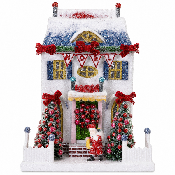 White glittered cardboard Santa cottage with snowy roof, red bows, and Noel bunting.
Christmas village cottage with Santa figure, decorated trees, white fence, and frosted sparkle.
Holiday Santa cottage decoration measuring 8.5 x 6.5 x 11 inches.