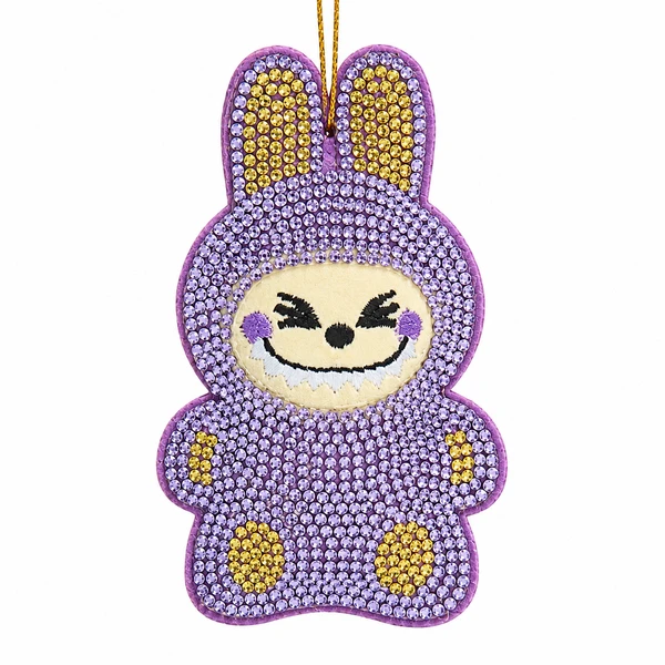 Purple bedazzled monster ornament with sparkling gem-covered body and bunny-style ears.
Embroidered smiling face with black eyes, white teeth, and purple cheeks.
3.5-inch Kurt Adler ornament made from fabric mâché, plastic, and polyester.