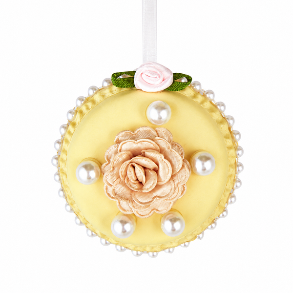Yellow round macaron ornament with a silk tea rose center, faux pearls around and on top, hanging from white ribbon.