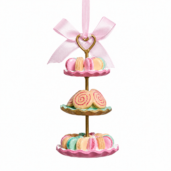 Three-tier tea snack ornament featuring pastel macarons and swirl cookies on decorative trays.
Kurt Adler dessert-themed ornament with gold-tone stand and pink ribbon bow.
5-inch resin and iron ornament styled as a tiered pastry display for holiday decorating.