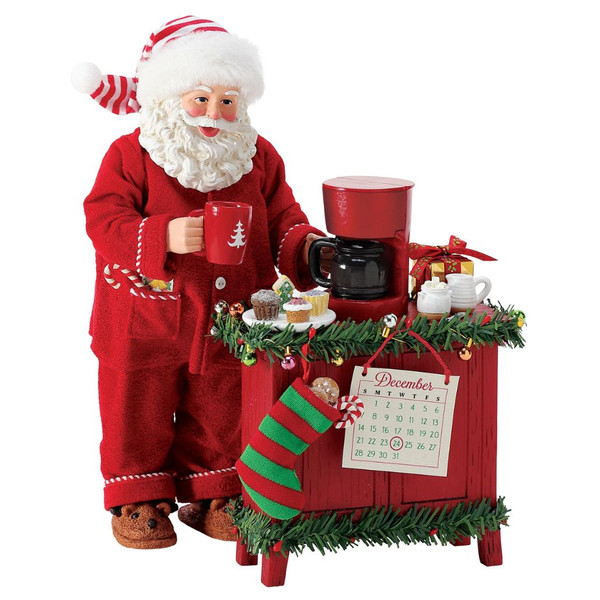 Department 56 Possible Dreams But First, Coffee Santa figurine with Santa holding a mug beside a red coffee station.
Santa in red pajamas and striped cap with coffee maker, cupcakes, stocking, garland, and December calendar.
Possible Dreams But First, Coffee Santa collectible measuring 10.5 inches high with Clothtique fabric details.
