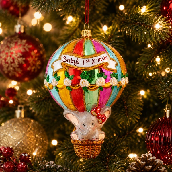 Huras Family Baby's First Christmas Balloon 5.7-inch handblown glass ornament.

Colorful hot air balloon Christmas ornament with pastel panels, gold trim, white flowers, and Baby's First Christmas banner.

Baby's first Christmas glass ornament featuring a small elephant with a red bow riding in a hot air balloon basket.