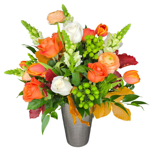 Bring the vibrant warmth of the season home with Mandarin Fall, featuring a luminous blend of vibrant orange roses, peach ranunculus, bright orange tulips, crisp white roses, green snapdragons, hypericum berries, and rich autumn foliage in a modern silver vessel.