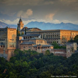 The Alhambra palace complex at golden hour with the Sierra Nevada mountains behind, Granada, Spain