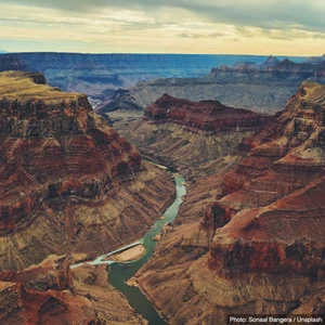 Aerial view of a river winding through deep red-rock canyon country in the American West