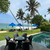 A beachfront resort on Sri Lanka's coast — pool, lawn and sun lounges under blue umbrellas, with palms and surf behind.