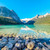 Clear turquoise water and rocky shoreline at Lake Louise with snow-capped peaks and pine forest, Banff National Park
