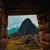 The ruins of Machu Picchu framed through a trapezoidal Inca stone window, with Huayna Picchu in cloud beyond.