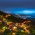 The hillside town of Jiufen in northern Taiwan lit up at dusk above the coast.