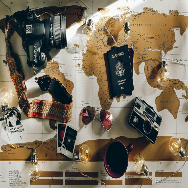 World map, a passport and a coffee in soft natural light. The decision behind every long-haul trip starts on paper. Photo by Charlotte Noelle on Unsplash.