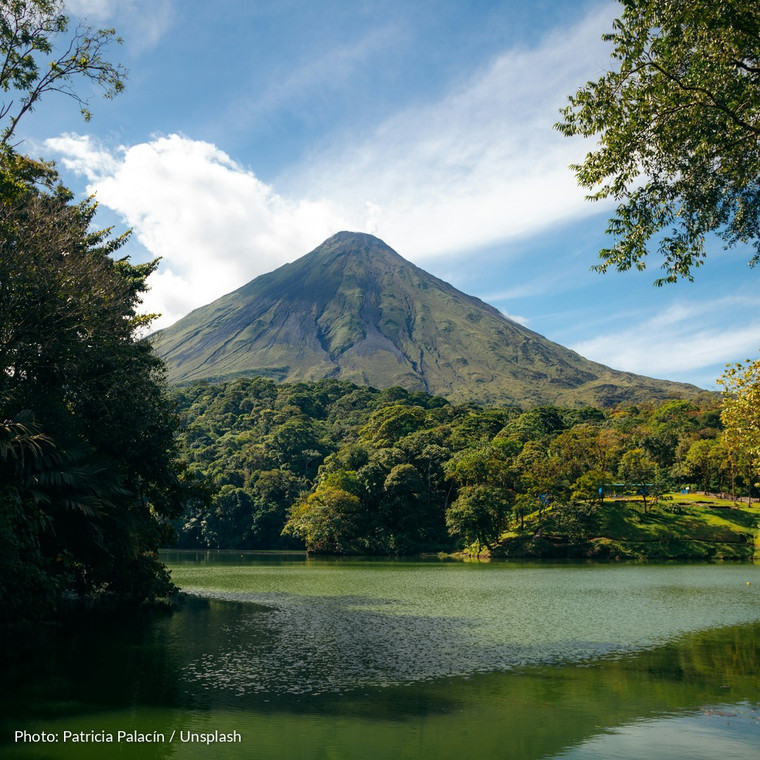 Arenal Volcano rising above rainforest, reflected in a calm lake in northern Costa Rica.