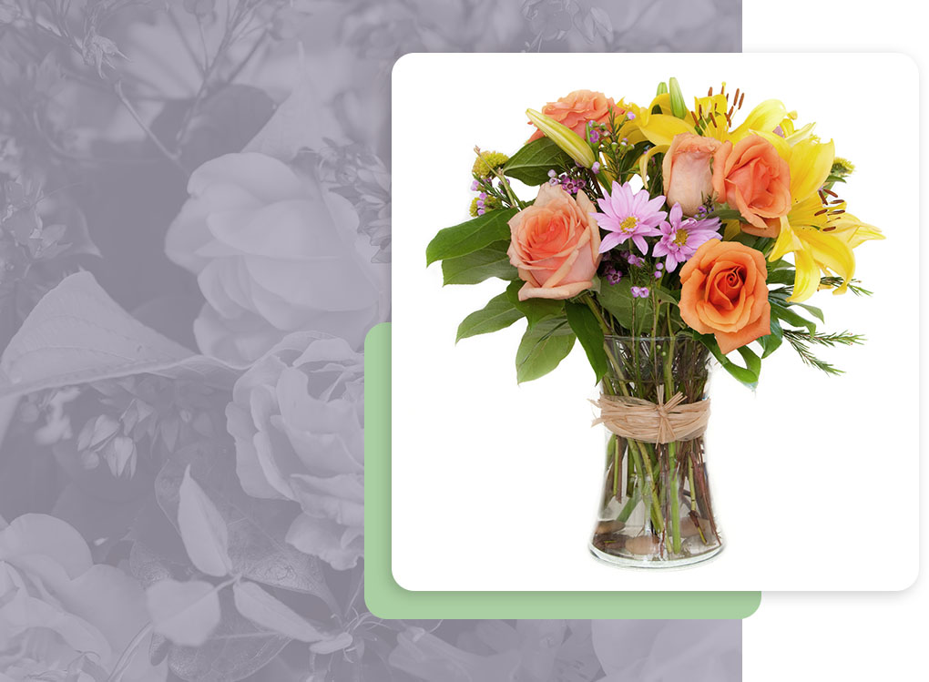 An image of a bouquet of peach, yellow, and pink flowers in a clear vase