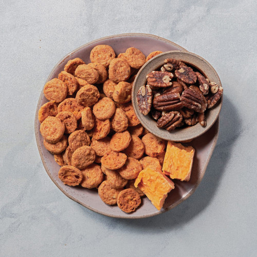 Pecan cheddar biscuits on plate with bowl of pecans and two blocks of cheddar cheese overhead