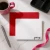 Holla Swash flat notecard with rounded corners and black Paige script, red envelope, pink coffee mug, silver pen, ribbon and black desk tray.