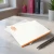Orange-bordered personalized flat notecard with orange monogram, envelope, and desk styling