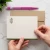 Olive-bordered personalized flat notecard with olive monogram and green envelope held by hand