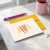 Personalized folded note card with an orange and yellow Traditional Script monogram, coordinating yellow envelope, pink pen, and coffee mug.