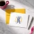 A2 folded monogram note card personalized in navy and yellow, shown with a coordinating yellow envelope, silver pen, and coffee.