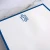 Close-up of blue-bordered personalized square notepad with blue monogram