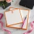 Orange personalized square notepads with monograms, pink ribbon, and pen