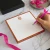Orange-bordered personalized square notepad with orange monogram and hand writing