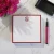 Red-bordered personalized square notepad with red monogram, flowers, and pink pen