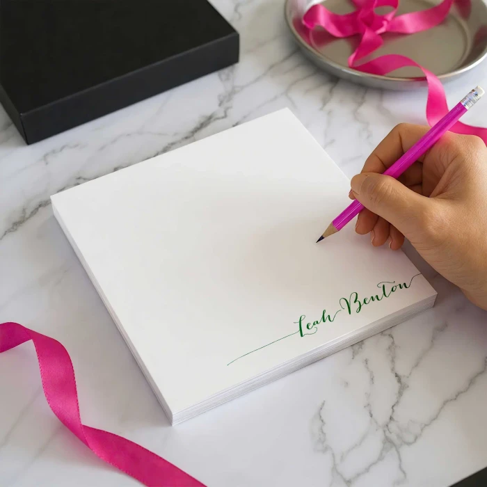 Simple Calligraphy personalized square notepad with a name printed at the bottom while someone writes