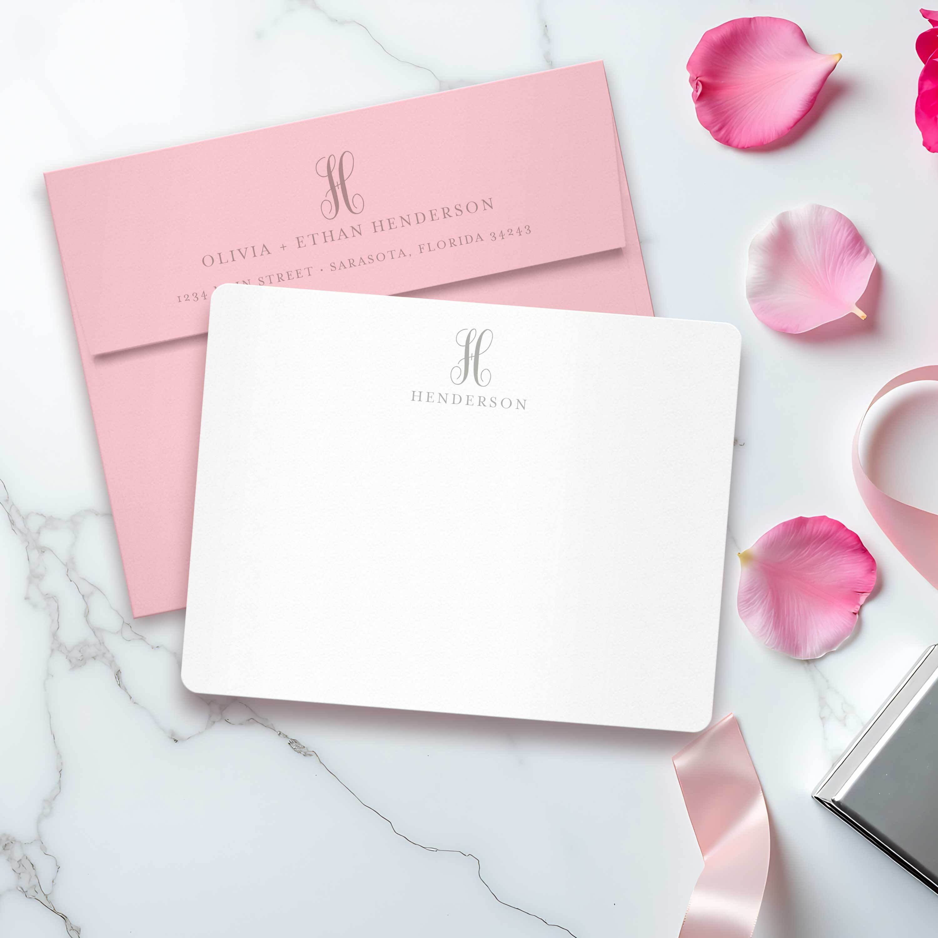 Personalized couple stationery set with monogrammed notecards and return addressed envelope — wedding gift flat lay with pink accents and ribbon