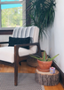 A purple soy candle burns gently on a wooden side table alongside an aloe plant in a cozy home interior.