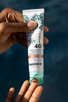 hands hold badger mineral sunscreen spf40 for face, tinted.