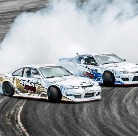 Two cars racing on a track with a cloud of dust trailing behind