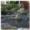 Pond netting installed over a backyard water feature with plants and rocks.