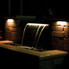 LED hardscape lights illuminating a nighttime waterfall feature in a backyard. LED hardscape lights illuminating a nighttime waterfall feature in a backyard.