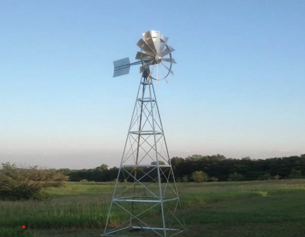 Four-legged windmill aerator installed in open field for pond aeration and water circulation.