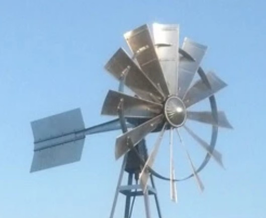 Windmill head with multi-blade rotor and tail vane for pond aeration system.