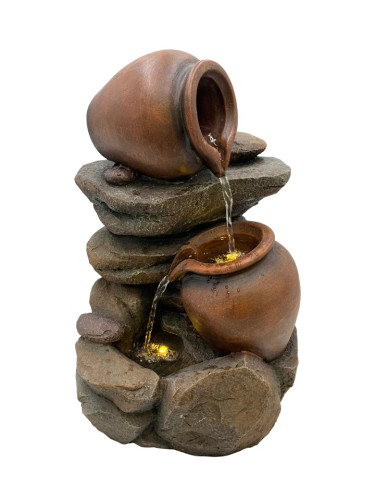 Close-up view of the water spout in an indoor/outdoor fountain, with water trickling down through smooth stones. Close-up view of the water spout in an indoor/outdoor fountain, with water trickling down through smooth stones.