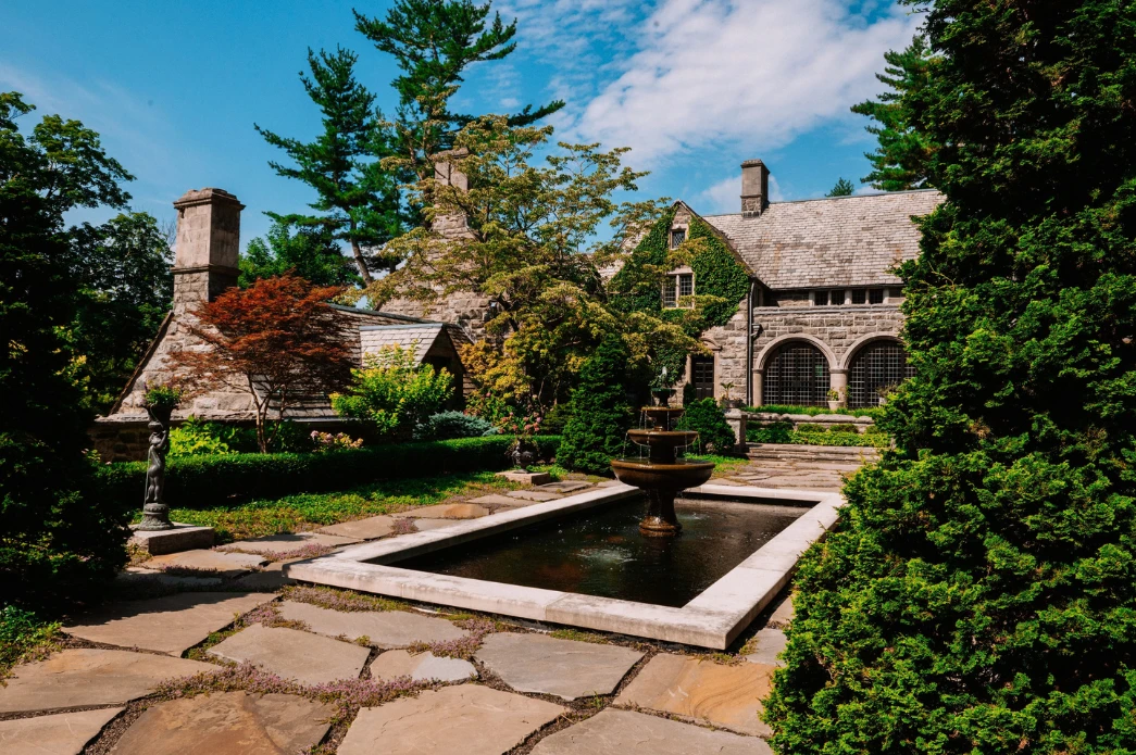 Formal fountain pool in front of a stone estate home