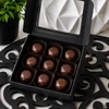 Open gift box of Baileys & Coffee artisan bonbons featuring glossy geometric chocolates in a premium black box. Cocktail-inspired chocolates handcrafted by Bomb Confections.